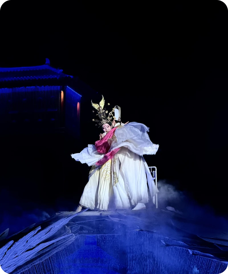 Traditional Chinese opera performers on a blue-lit stage